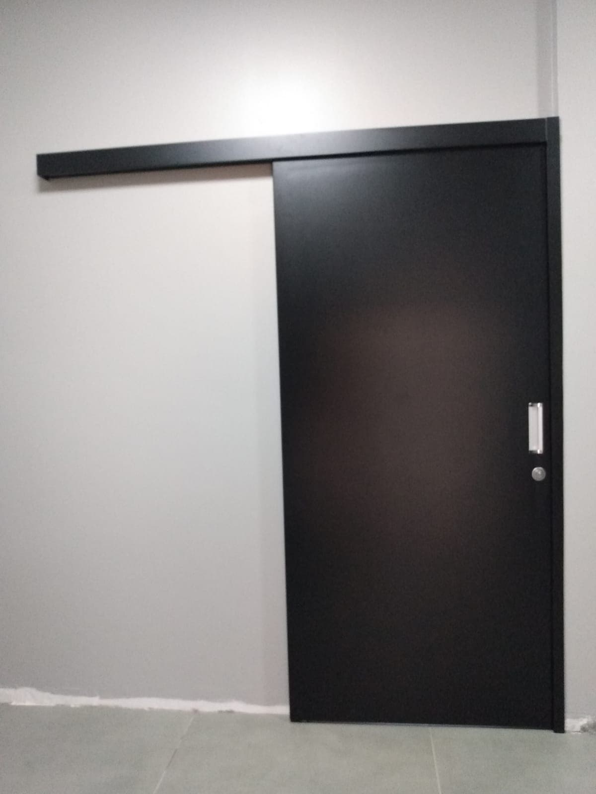 Porta preta de correr com trilho aparente