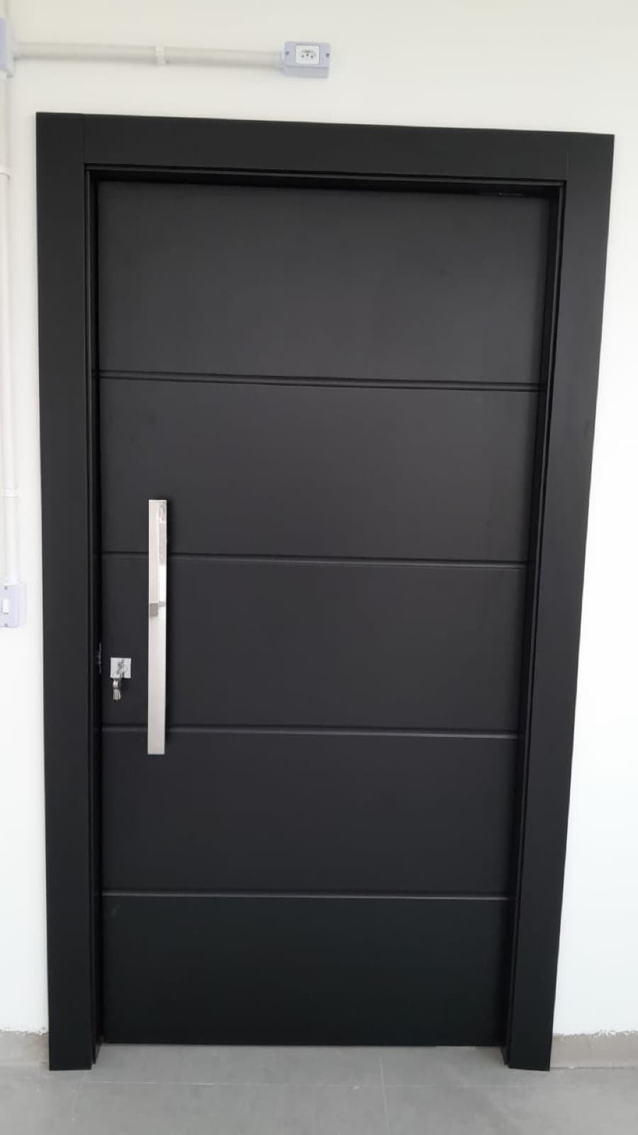 Porta preta com frisos horizontais e puxador vertical