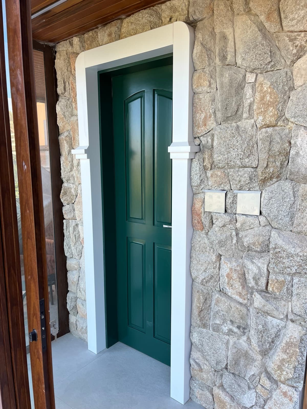 Porta verde em fachada com pedra aparente
