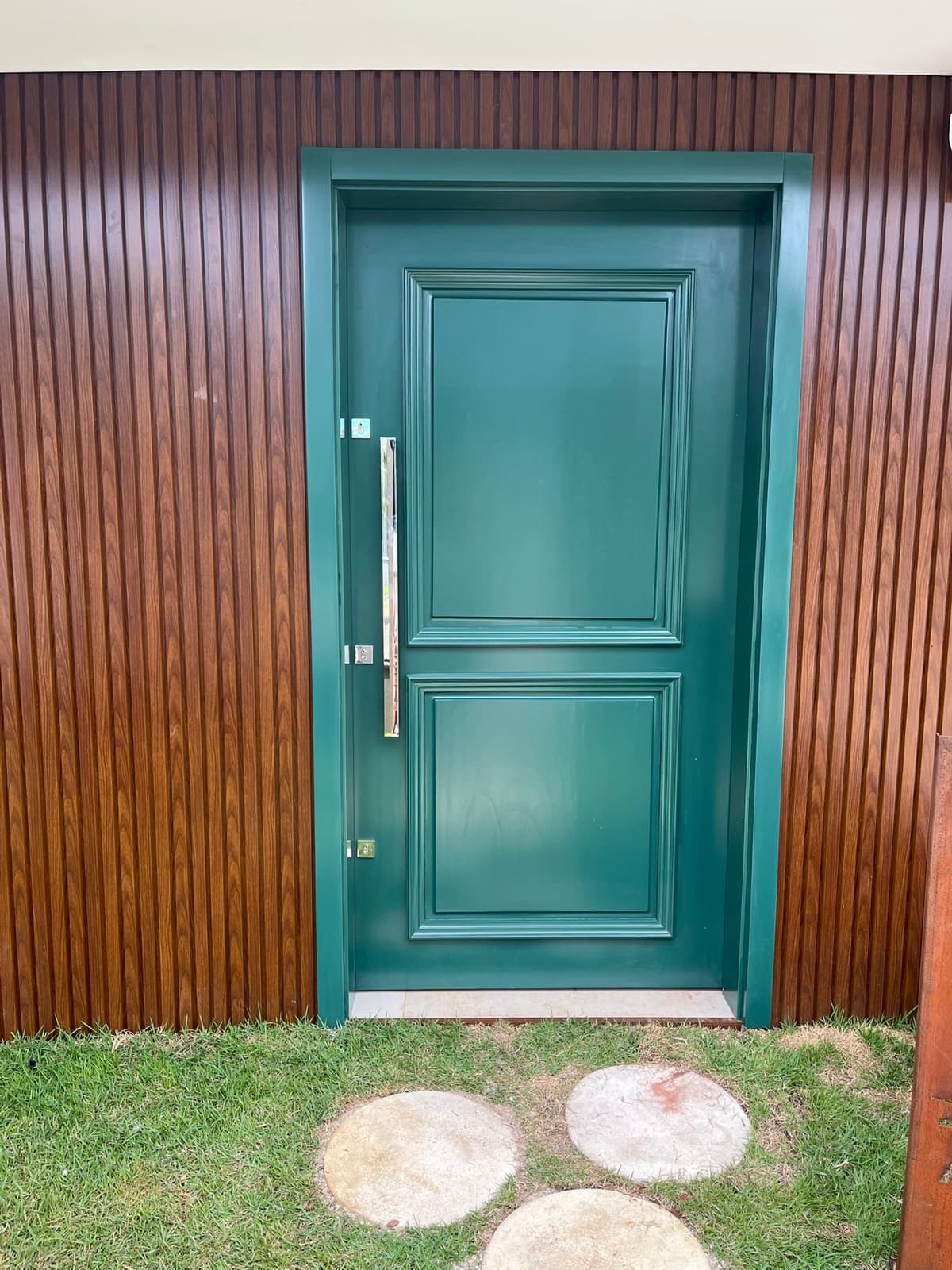 Porta verde instalada com painel ripado amadeirado