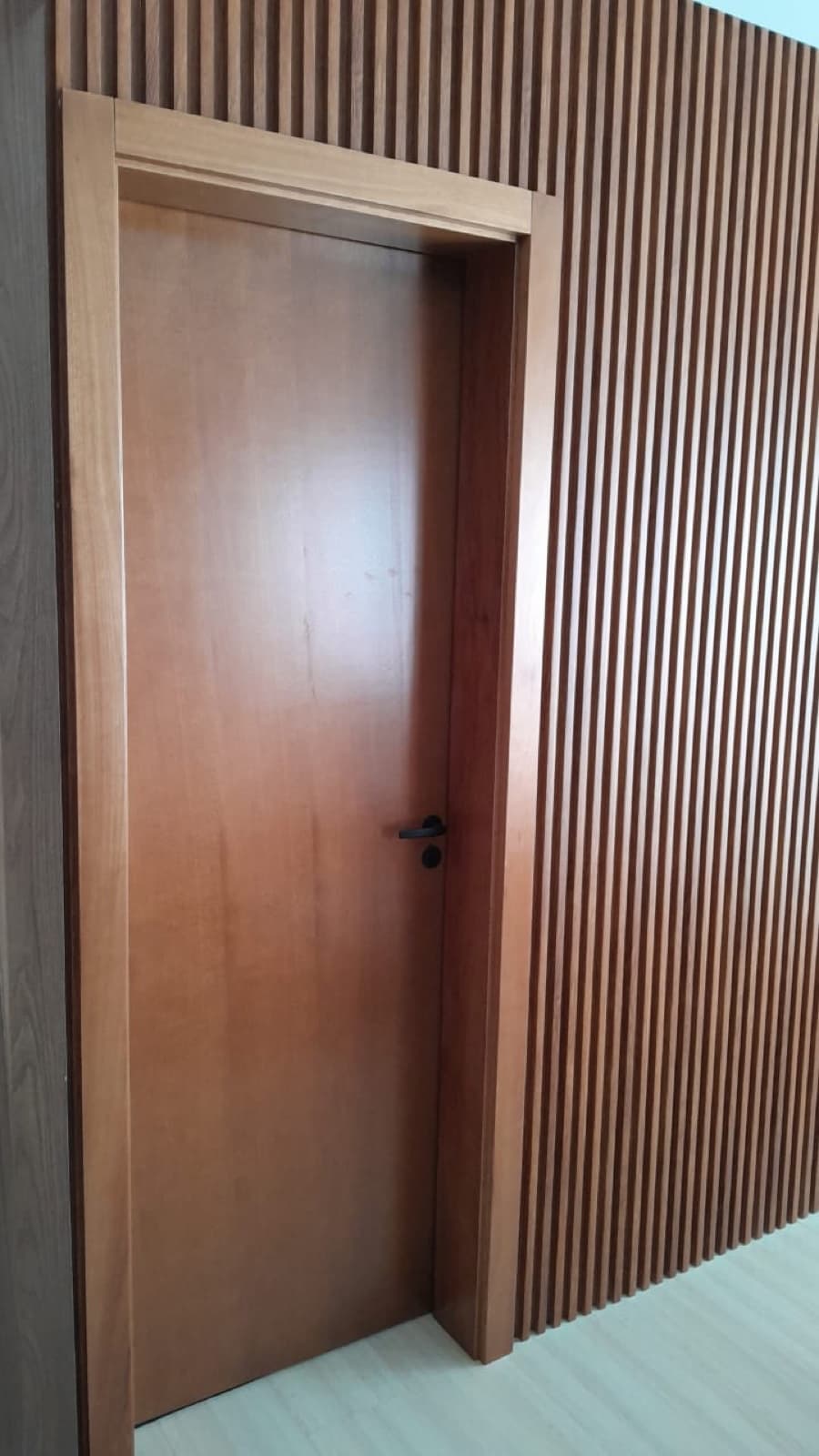 Porta em acabamento amadeirado com painel ripado